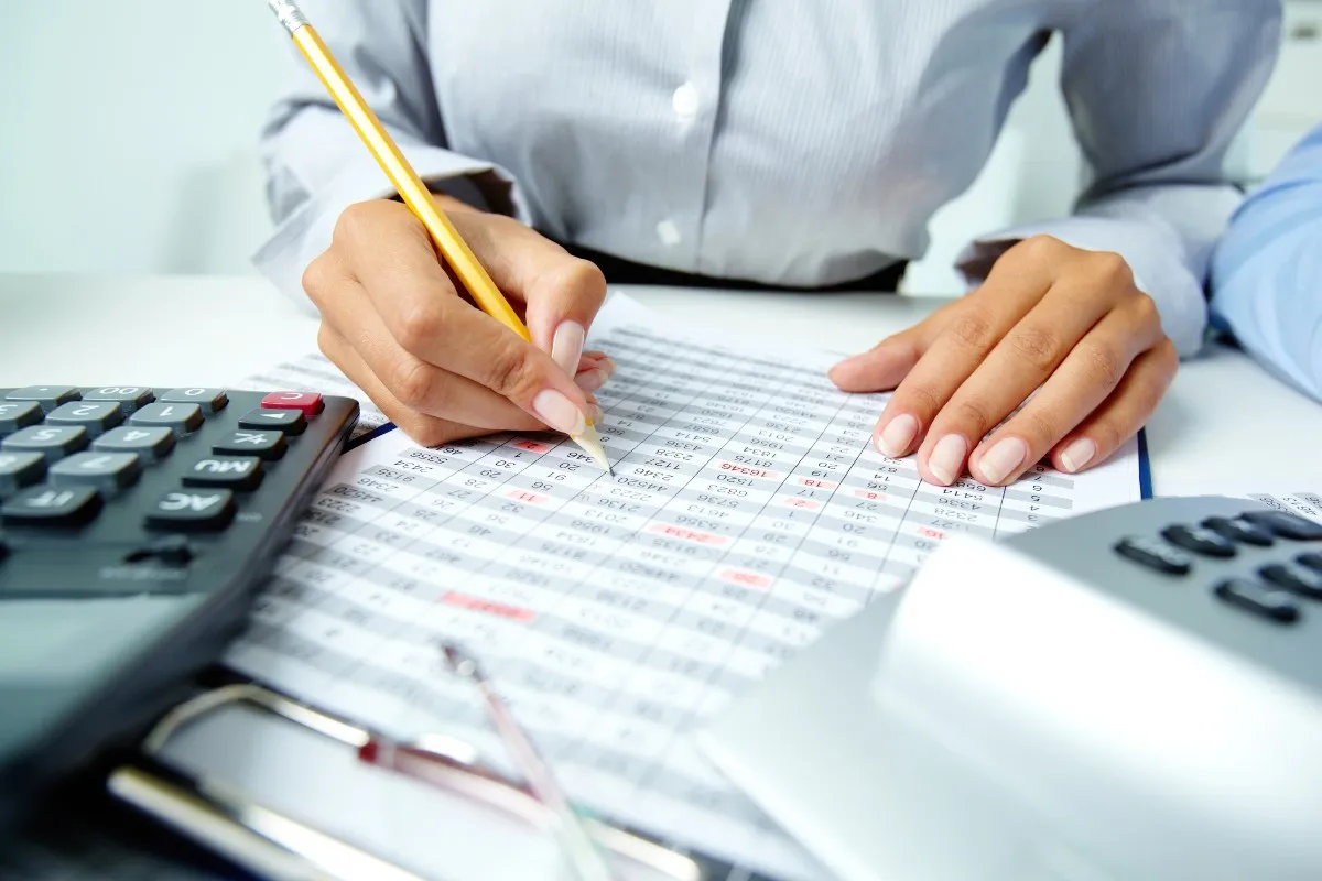 Person calculating financial data with a calculator and spreadsheet at a desk – Best CMA Training Center in Qatar.