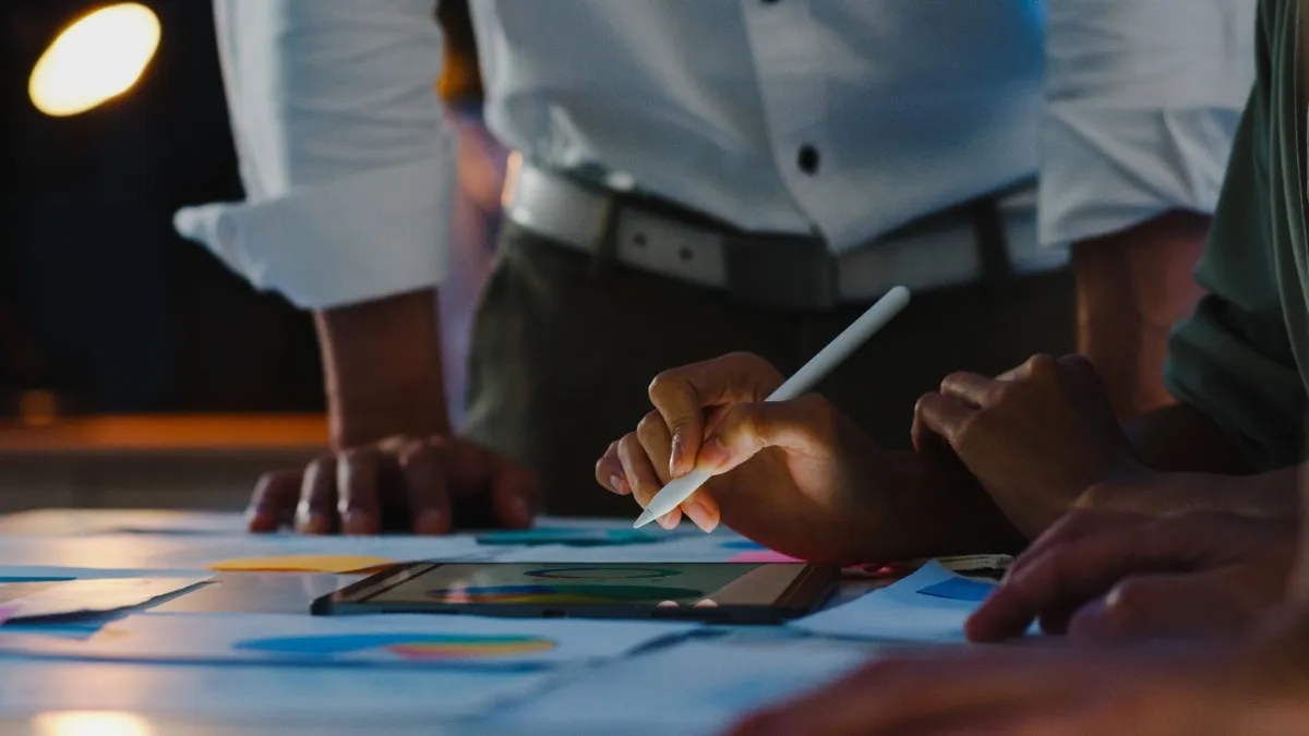 Professionals collaborating on a digital tablet during a brainstorming session on how to get PMP certification in Qatar 2026